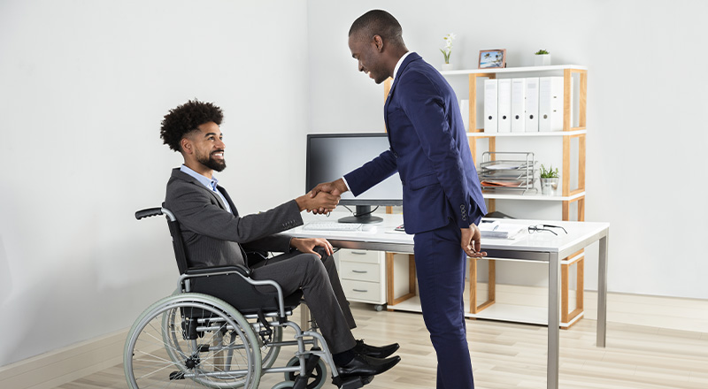 black business man in wheelchair shaking an associate's hand